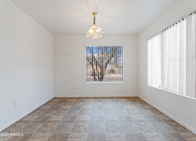 unfurnished room with a healthy amount of sunlight, baseboards, and a chandelier