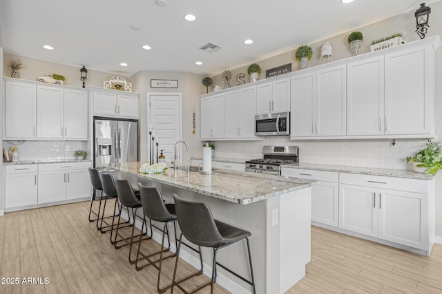 2343 E Kelly Dr, Gilbert, AZ 85298 - kitchen featuring appliances with stainless steel finishes, tasteful backsplash, a kitchen island with sink, white cabinetry, and recessed lighting