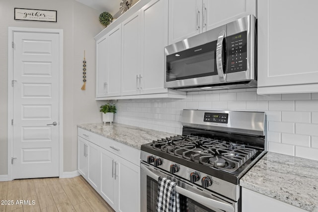 2343 E Kelly Dr, Gilbert, AZ 85298 - kitchen with appliances with stainless steel finishes, white cabinets, decorative backsplash, and light wood-style flooring