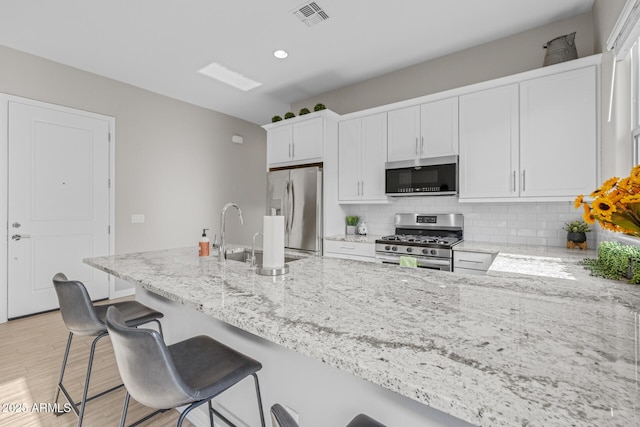 2343 E Kelly Dr, Gilbert, AZ 85298 - kitchen featuring appliances with stainless steel finishes, a sink, light stone countertops, backsplash, and white cabinetry