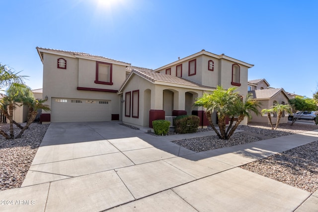 mediterranean / spanish-style home with a garage, driveway, a tiled roof, and stucco siding