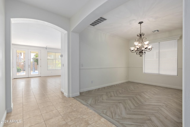 unfurnished room with french doors, light tile patterned floors, ornamental molding, and an inviting chandelier