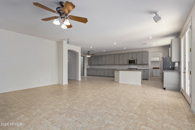 unfurnished living room featuring ceiling fan, arched walkways, a sink, and recessed lighting