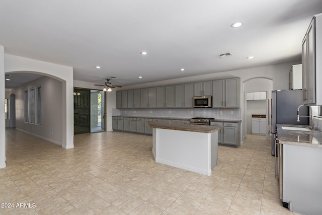 kitchen with visible vents, appliances with stainless steel finishes, a center island, gray cabinetry, and backsplash