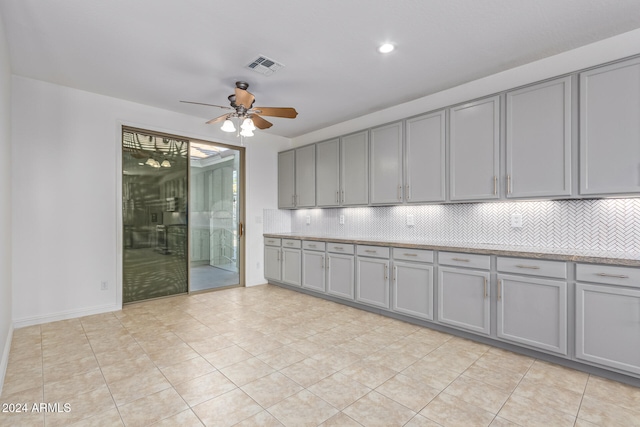 kitchen featuring backsplash, gray cabinets, ceiling fan, and light tile patterned floors