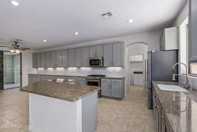 kitchen featuring gray cabinetry, ceiling fan, sink, stainless steel appliances, and tasteful backsplash