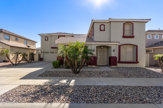 view of front of home featuring driveway, a tiled roof, an attached garage, and stucco siding