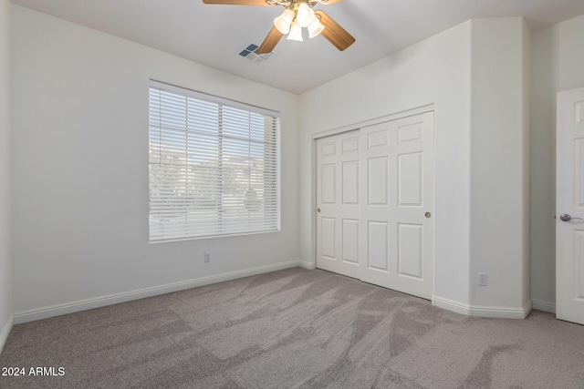 unfurnished bedroom featuring ceiling fan, light carpet, and a closet