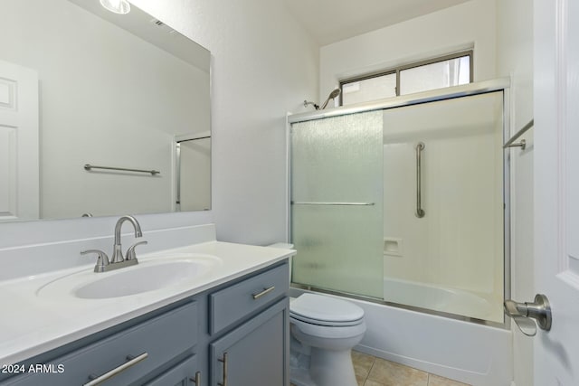 bathroom featuring toilet, shower / bath combination with glass door, tile patterned flooring, and vanity