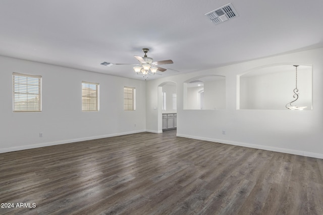 unfurnished living room with dark wood-type flooring, visible vents, baseboards, and a ceiling fan