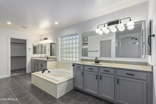 full bath with a walk in closet, two vanities, a sink, tile patterned flooring, and a bath