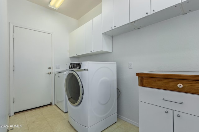 clothes washing area featuring cabinet space, washing machine and dryer, and baseboards