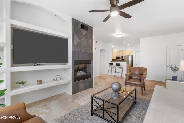 living room featuring ceiling fan and a tile fireplace