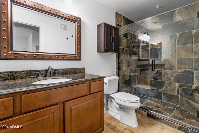 bathroom with vanity, toilet, a shower with shower door, and tile patterned flooring