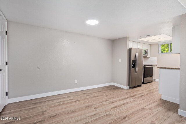 kitchen with light hardwood / wood-style flooring, stainless steel appliances, and white cabinets