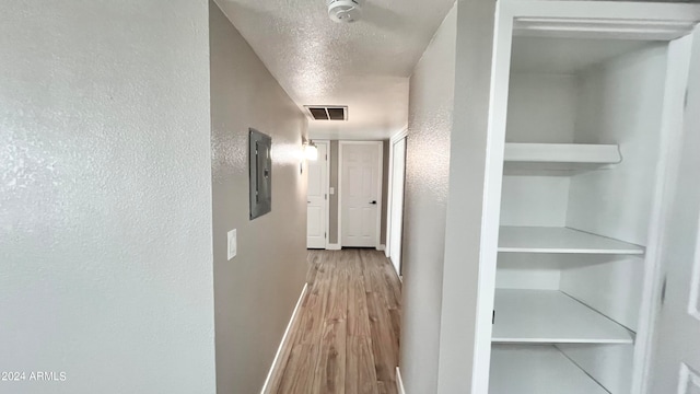 hall featuring electric panel, a textured ceiling, and hardwood / wood-style flooring