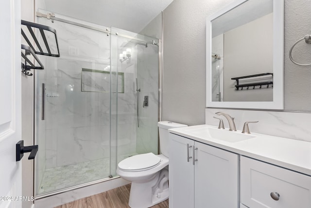 bathroom with walk in shower, hardwood / wood-style floors, vanity, and toilet