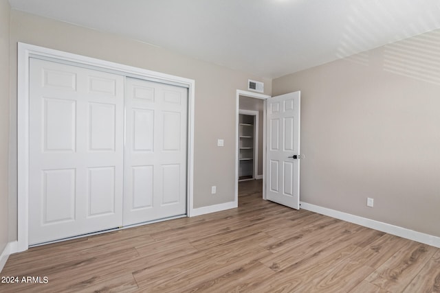 unfurnished bedroom featuring light hardwood / wood-style flooring and a closet