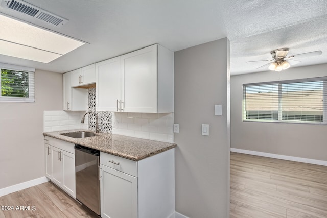 kitchen featuring decorative backsplash, white cabinetry, dishwasher, and sink