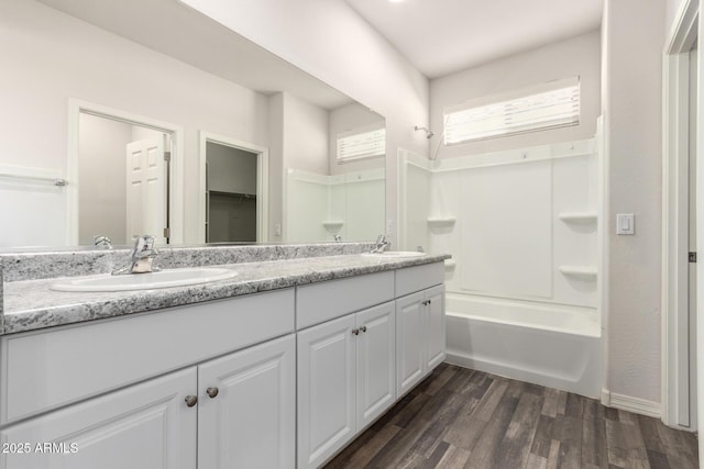 bathroom featuring double vanity, wood finished floors, shower / tub combination, and a sink