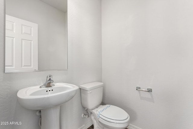 half bath featuring toilet and baseboards