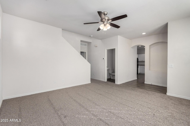 unfurnished living room with arched walkways, baseboards, and carpet