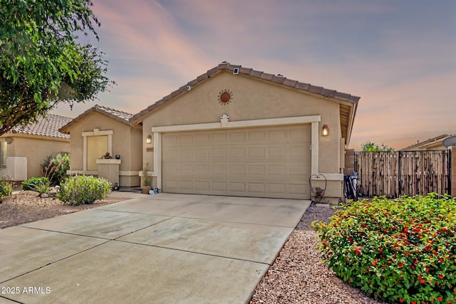 single story home with a tiled roof, driveway, a garage, fence, and stucco siding
