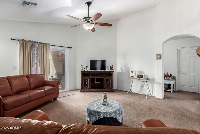 living area featuring a ceiling fan, visible vents, arched walkways, high vaulted ceiling, and carpet flooring