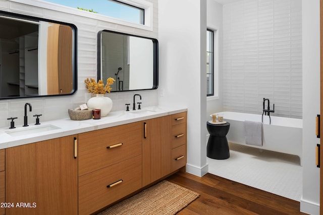 bathroom featuring vanity, wood-type flooring, a washtub, and backsplash