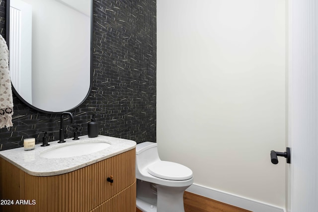 bathroom with vanity, toilet, wood-type flooring, and decorative backsplash