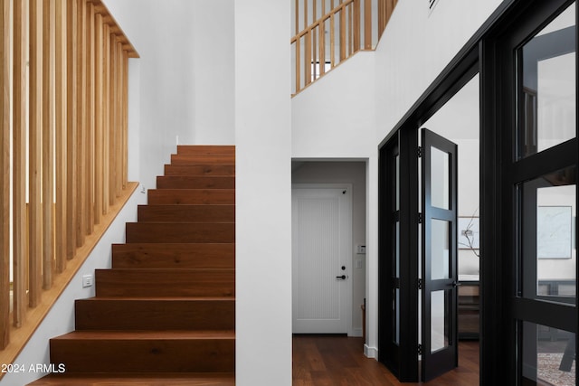 staircase featuring hardwood / wood-style floors, a healthy amount of sunlight, and a high ceiling