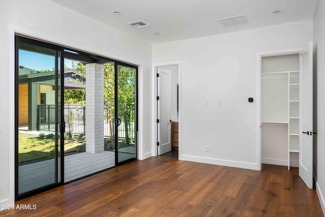 unfurnished bedroom featuring a closet, dark hardwood / wood-style floors, and access to exterior