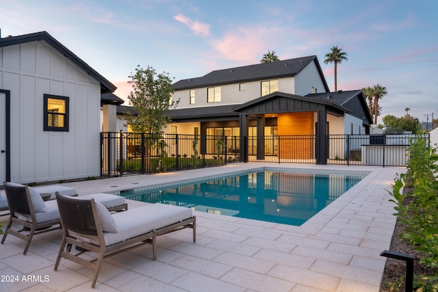 pool at dusk with a patio area