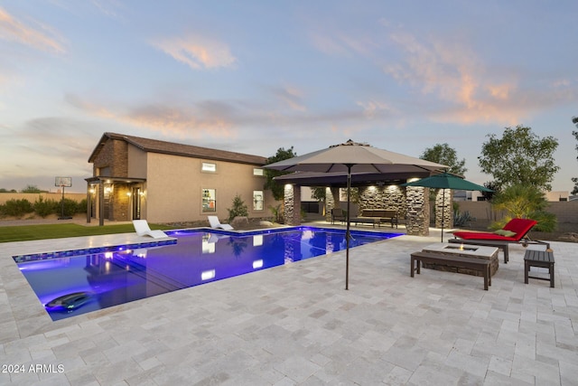 pool at dusk with a gazebo and a patio