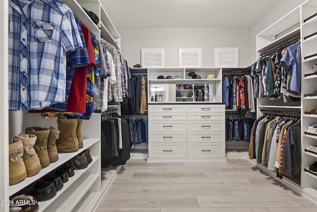 walk in closet with light hardwood / wood-style flooring