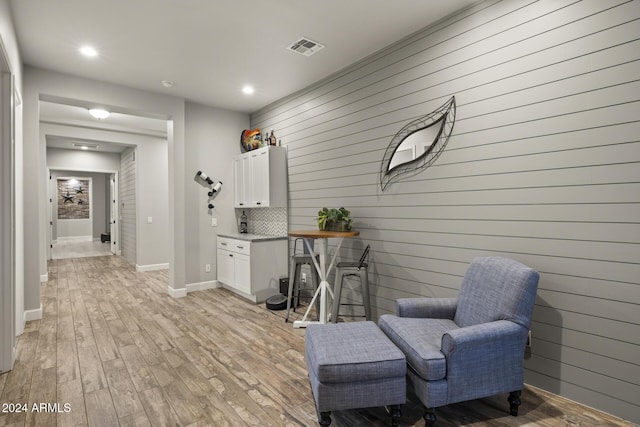 living area with light hardwood / wood-style flooring and wooden walls