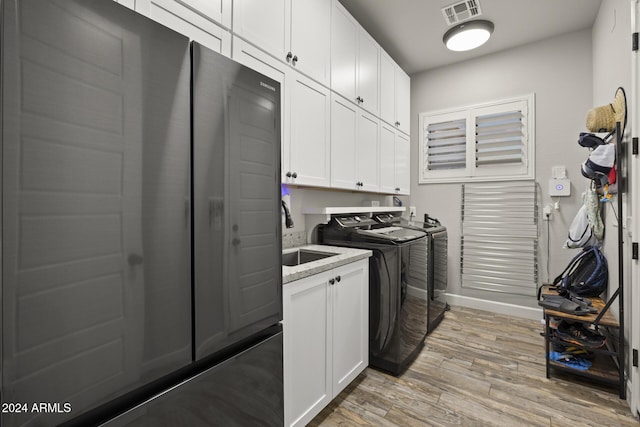 laundry room with cabinets, sink, independent washer and dryer, and light wood-type flooring