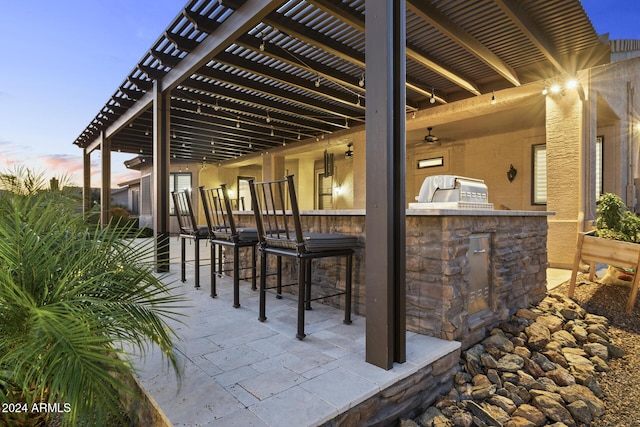 patio terrace at dusk featuring area for grilling, a pergola, and an outdoor bar