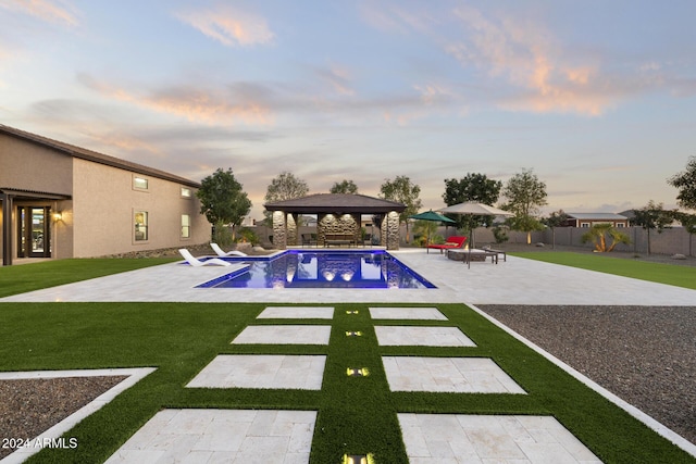 pool at dusk featuring a gazebo, a patio area, and a lawn