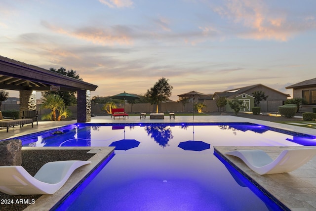 pool at dusk with a gazebo and a patio