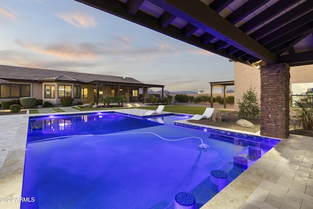 pool at dusk with a patio area