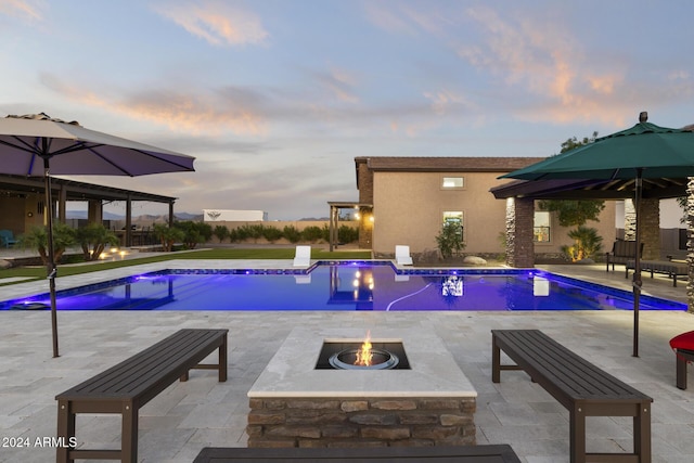 pool at dusk featuring a fire pit and a patio area