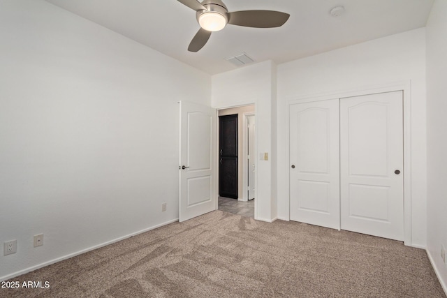 unfurnished bedroom featuring ceiling fan, a closet, and light carpet