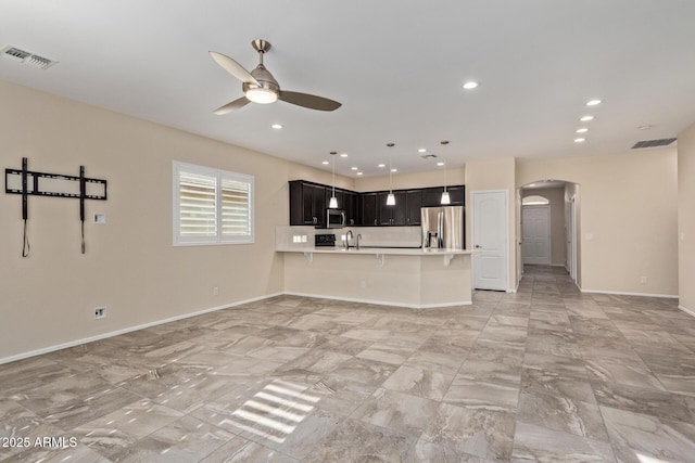 kitchen featuring appliances with stainless steel finishes, a breakfast bar, sink, ceiling fan, and kitchen peninsula