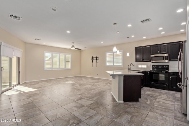 kitchen with a breakfast bar, sink, a wealth of natural light, pendant lighting, and stainless steel appliances