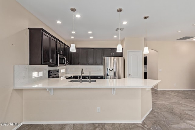 kitchen with tasteful backsplash, stainless steel appliances, decorative light fixtures, and kitchen peninsula