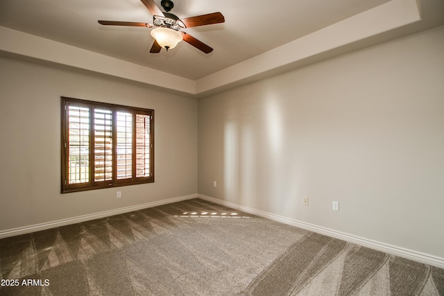 carpeted empty room featuring a tray ceiling and ceiling fan