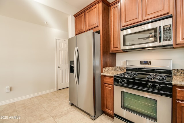 kitchen featuring light stone countertops, stainless steel appliances, and light tile patterned floors