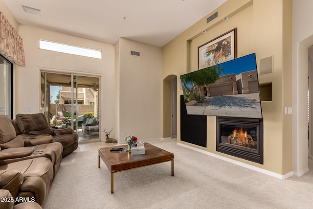 8324 E Cactus Wren Rd, Scottsdale, AZ 85250 - living area featuring arched walkways, carpet floors, and a glass covered fireplace