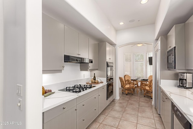 8324 E Cactus Wren Rd, Scottsdale, AZ 85250 - kitchen with under cabinet range hood, black appliances, arched walkways, recessed lighting, and light tile patterned floors